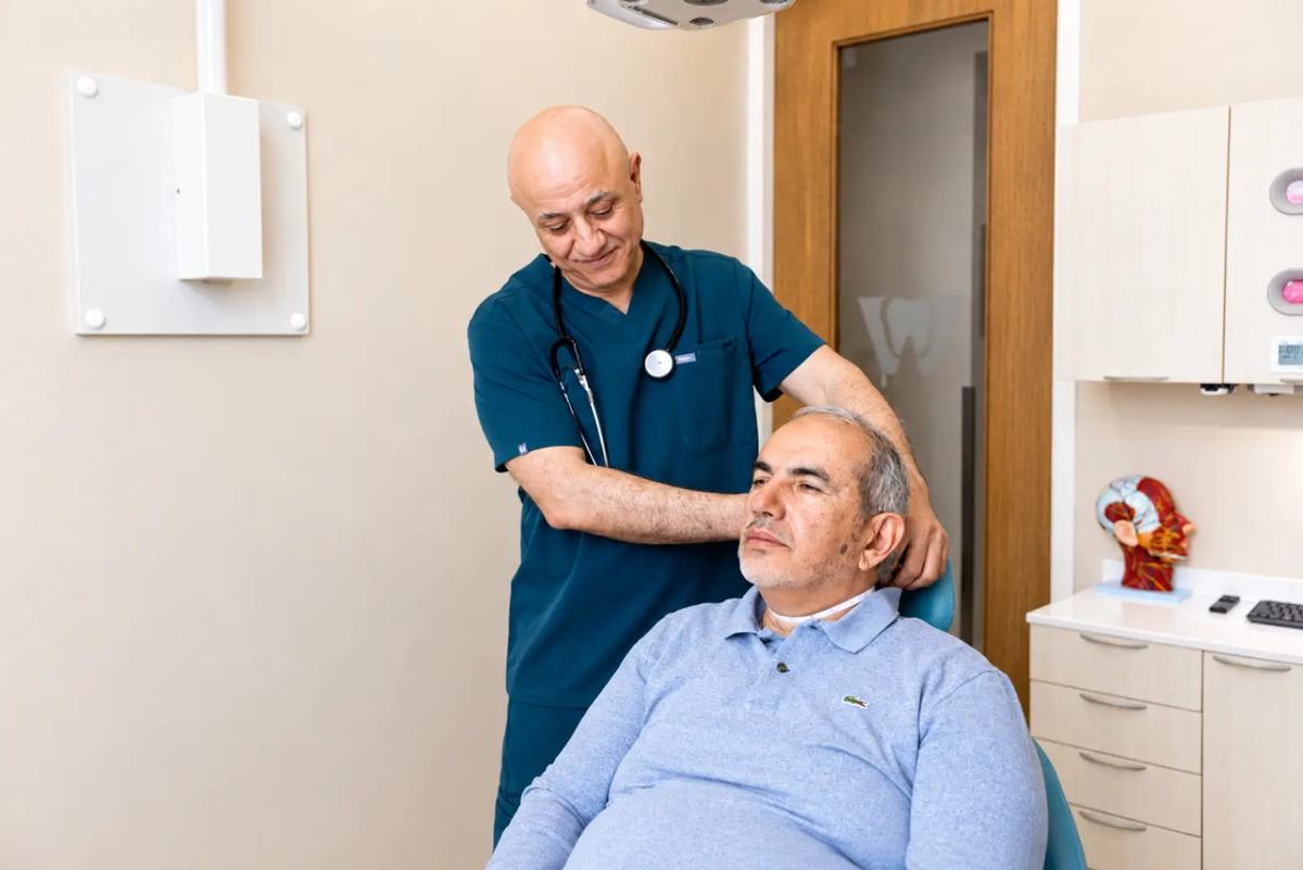 Dr. Sabah Jarullah examining a patient's neck and jaw during a sleep assessment at Westside, Calgary SW