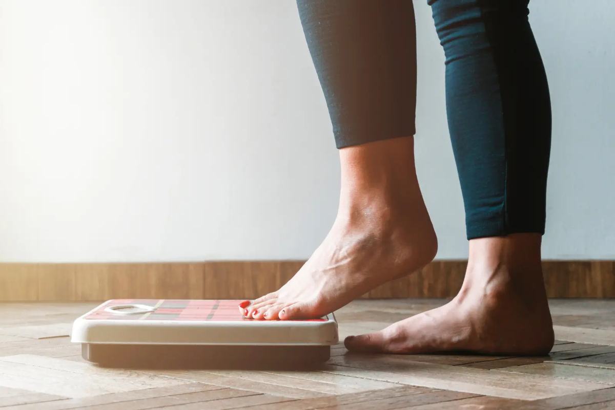 A person stepping onto a scale as part of physician-led weight management