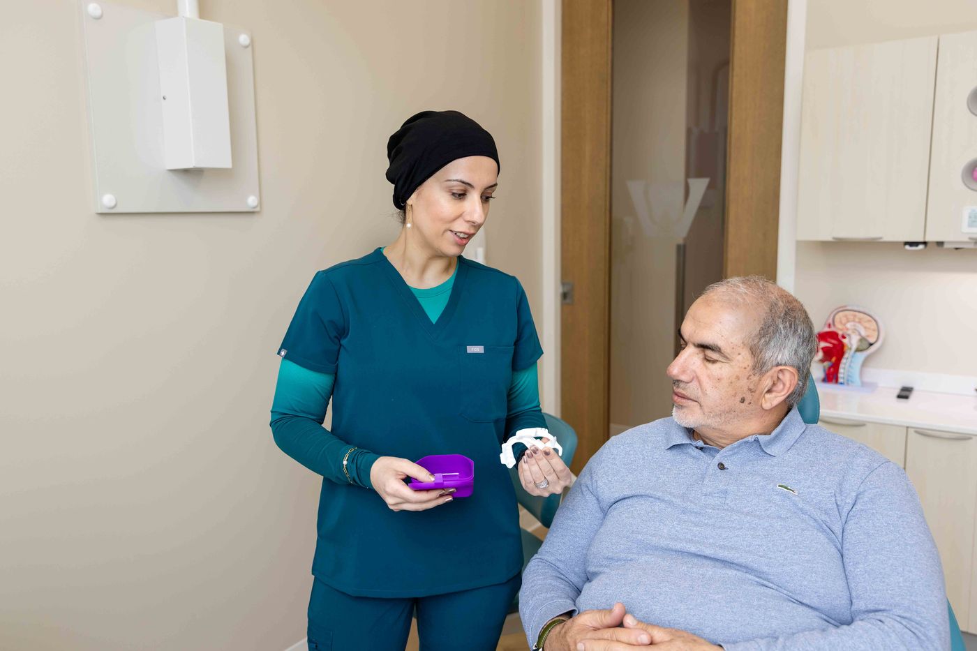 Dr. Zubaida Hussain showing a custom oral sleep appliance to a patient at Westside, Calgary SW